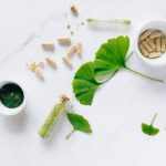 Flat lay of herbal supplements with ginkgo leaves on marble surface, emphasizing natural health remedies.